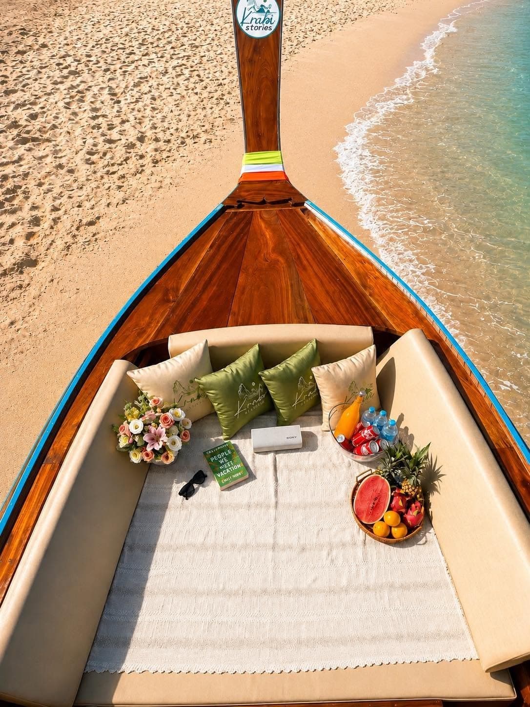 The cushioned bow seen from above, picnic and fresh fruit set out on the sand's edge