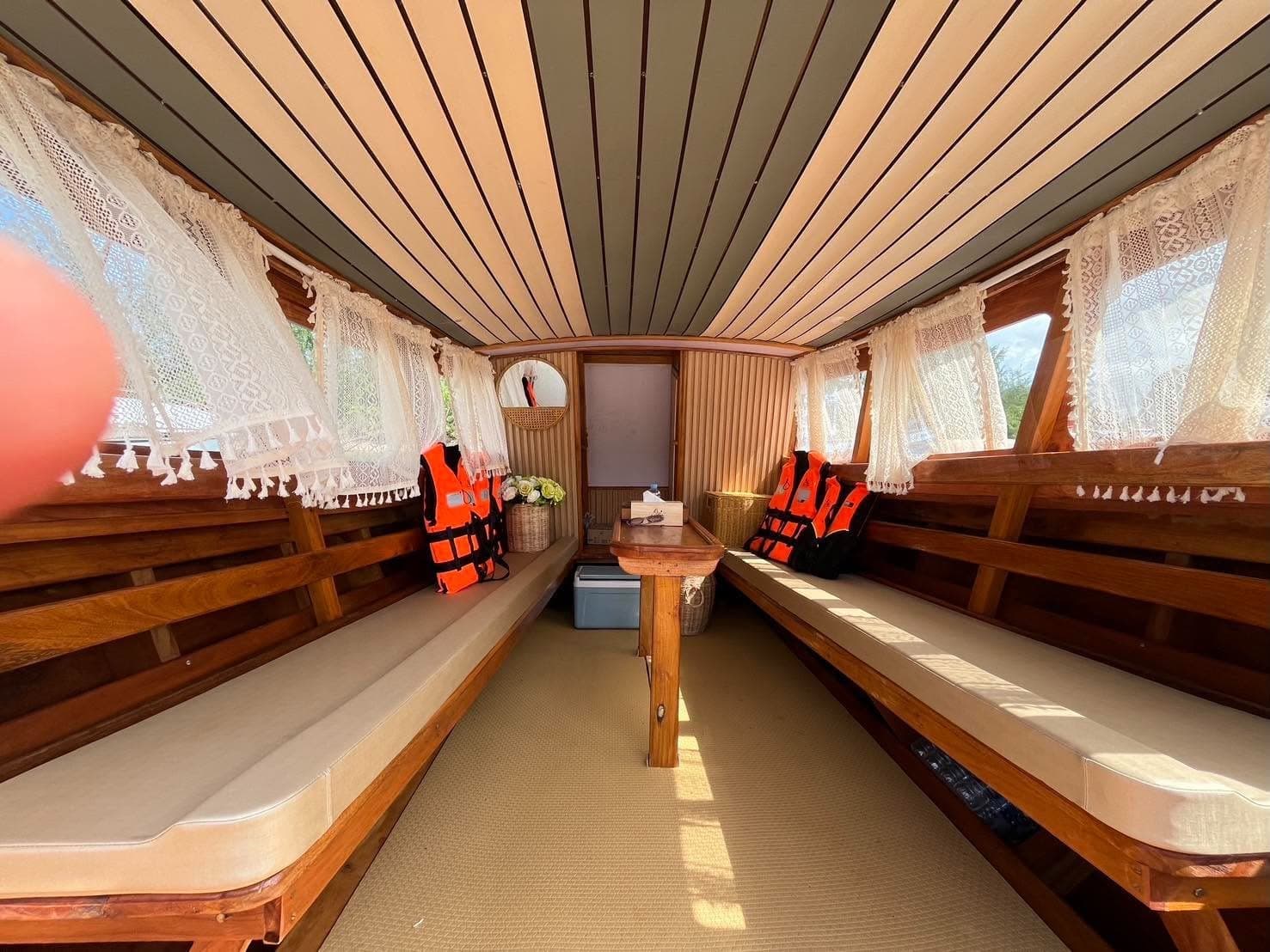 Inside the boat: cushioned benches, lace curtains and life jackets