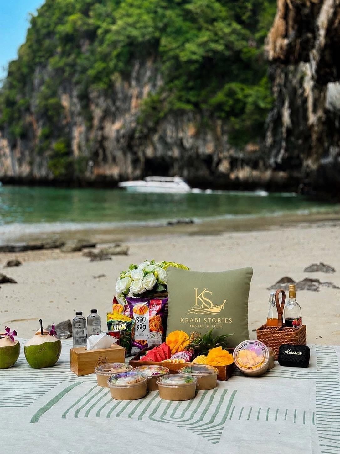 The beach picnic set-up: fresh fruit, drinks, speaker and the Krabi Stories cushion